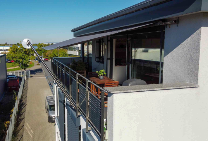 Ein Balkon mit Tisch und Stühlen, GFS Sonnensegel spendet Schatten.